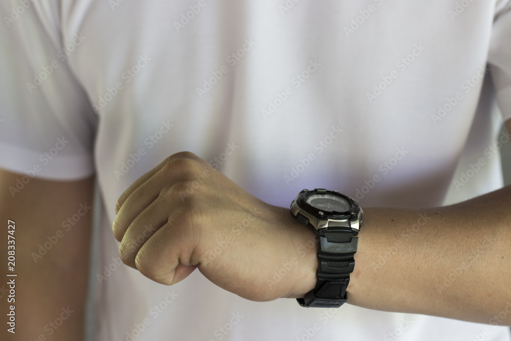 A man's hand with a clock against a white T-shirt. The concept of time, time management