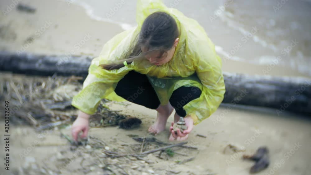 Happy girl walking along the coast Traveling Lifestyle adventure vacation outdoors. A girl dressed in a fashionable yellow raincoat Happy girl walking along the coast Traveling Lifestyle adventure vacation outdoors. A girl dressed in a fashionable yellow raincoat