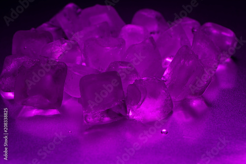 A pile of ice cubes in purple on a reflecting table