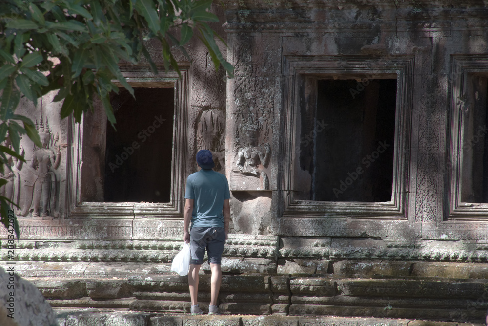 Angkor Cambodia, tourist looking at detail on the east gate to 12th century Angkor Wat temple Angkor Cambodia, tourist looking at detail on the east gate to 12th century Angkor Wat temple