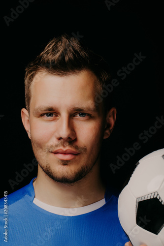 Close-up portrait of young handsome football player soccer posing on dark background. photo