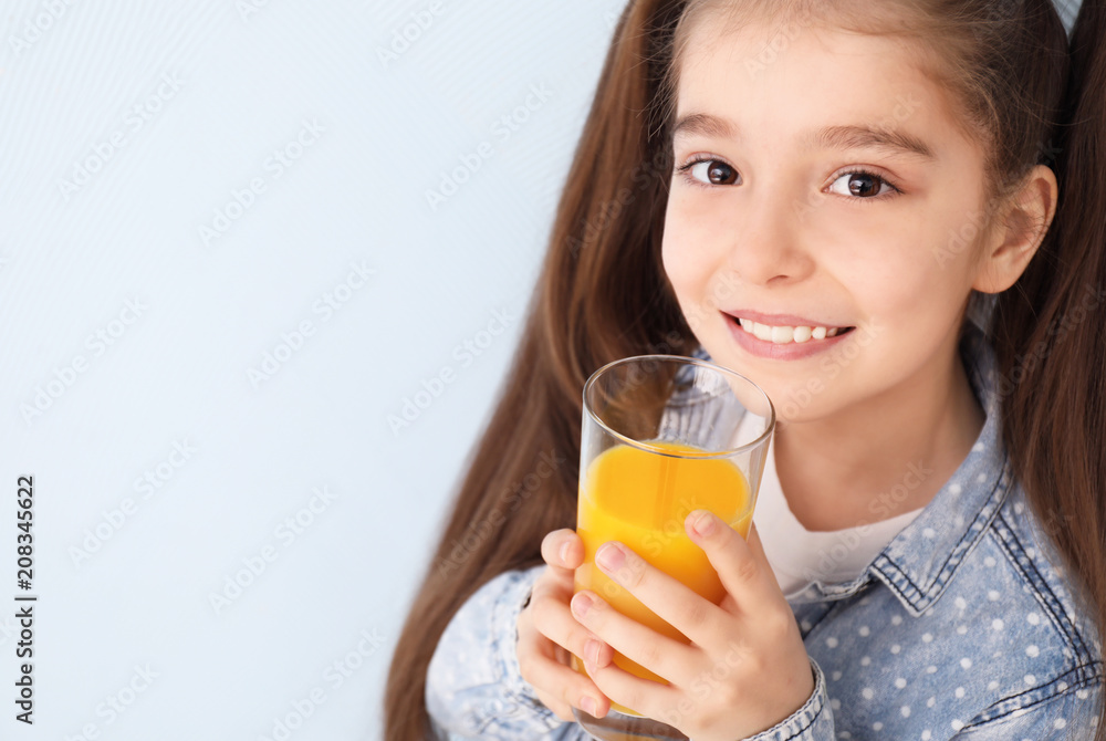 Funny little girl drinking citrus juice on color background Funny little girl drinking citrus juice on color background