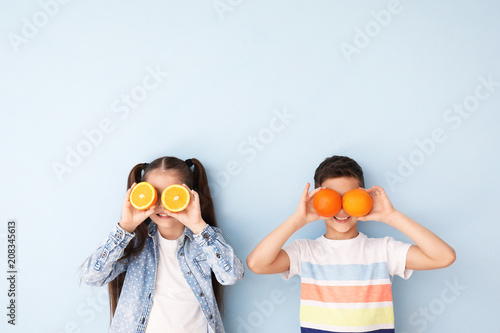 Canvas Print Funny little children with citrus fruit on color background