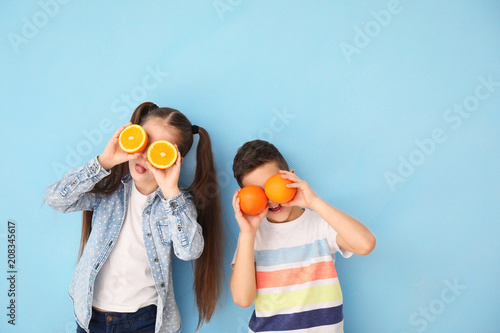 Photo Funny little children with citrus fruit on color background