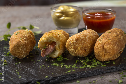 Fresh dough balls filled with sausage and cheese on a dark slate