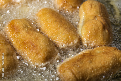 Frying dough balls filled with sausage and cheese in sunflower oil © Sebastian Studio
