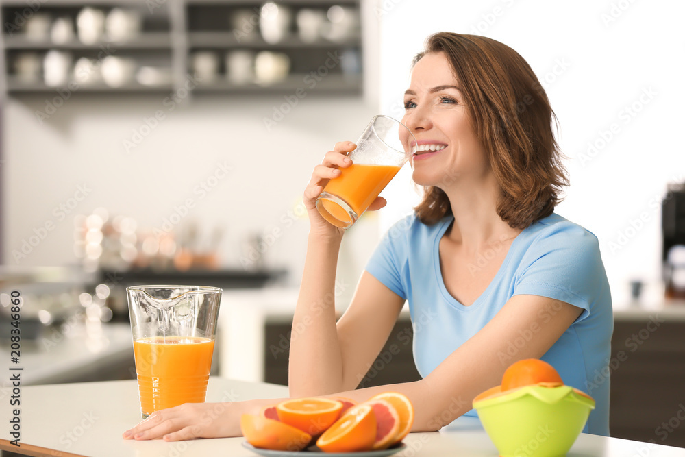 Beautiful woman drinking citrus juice in kitchen Beautiful woman drinking citrus juice in kitchen