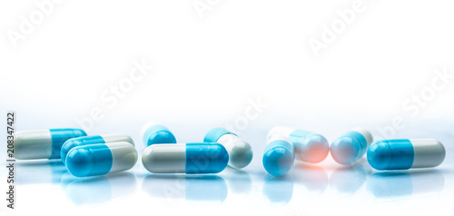 Blue and white capsules pill spread on white background with shadow and copy space. Global healthcare concept. Antibiotics drug resistance. Antimicrobial capsule pills. Pharmaceutical industry. photo