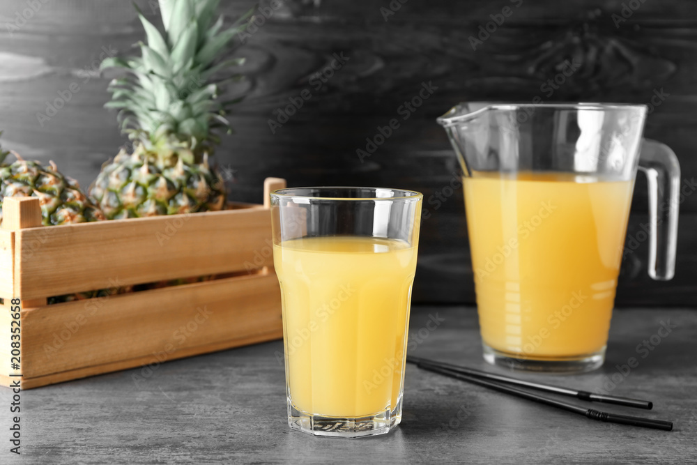 Glass and jug of tasty fresh pineapple juice on table Glass and jug of tasty fresh pineapple juice on table