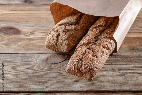 Wallpaper Mural Appetizing baguettes with sesame seeds and nuts in a paper bag on a wooden background. Healthy Food Concept Torontodigital.ca