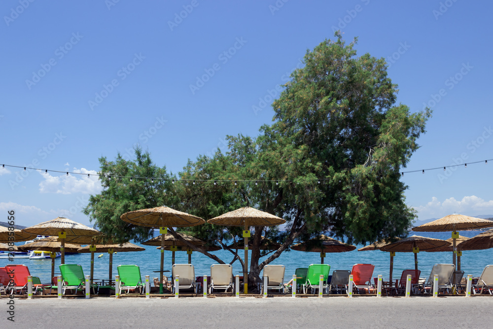 Beach straw umbrellas and sunbeds in the morning sunlight. Concept-  tourism, vacation by the sea.