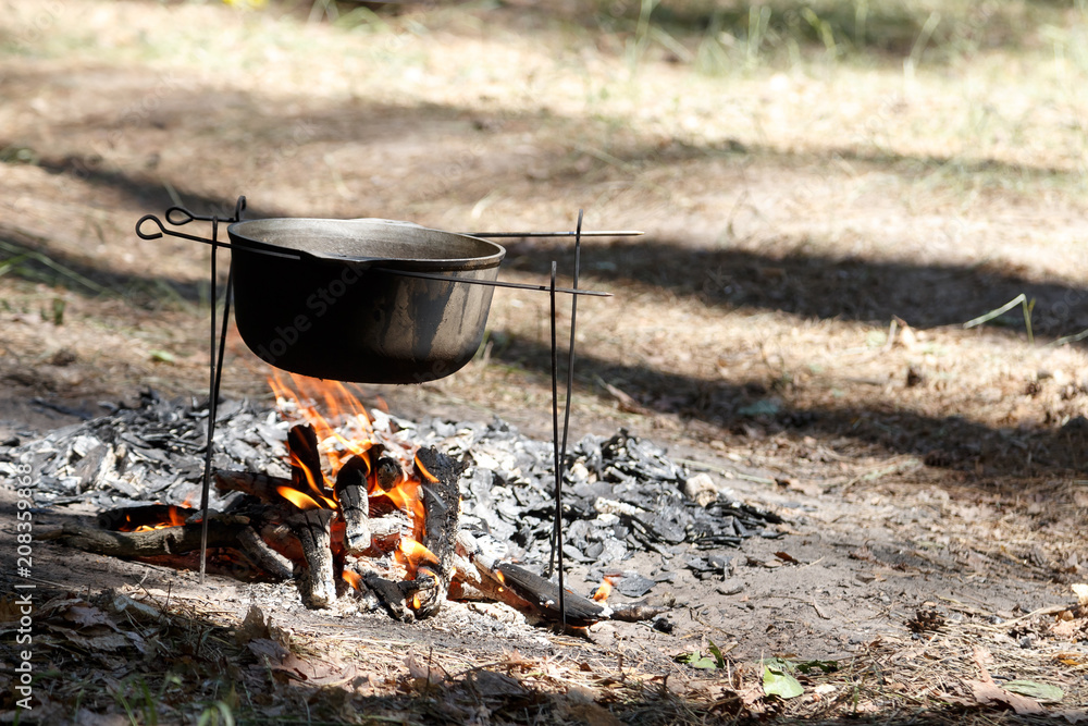 Outdoor food on fire in a camp. Camping - kettle over campfire Outdoor food on fire in a camp. Camping - kettle over campfire