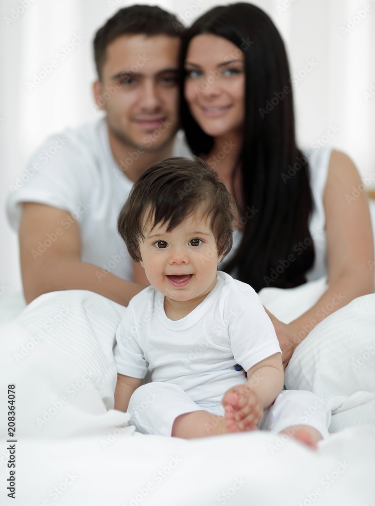 Happy couple and son sitting in bed