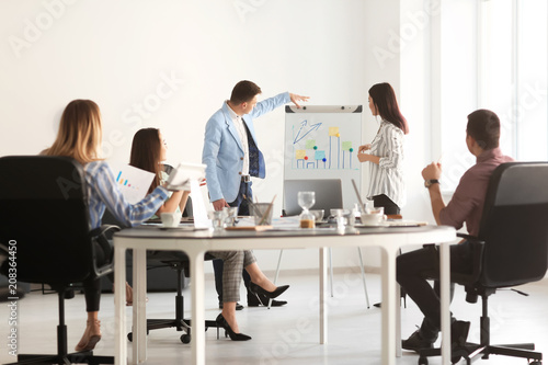 Young people giving presentation during business meeting in office