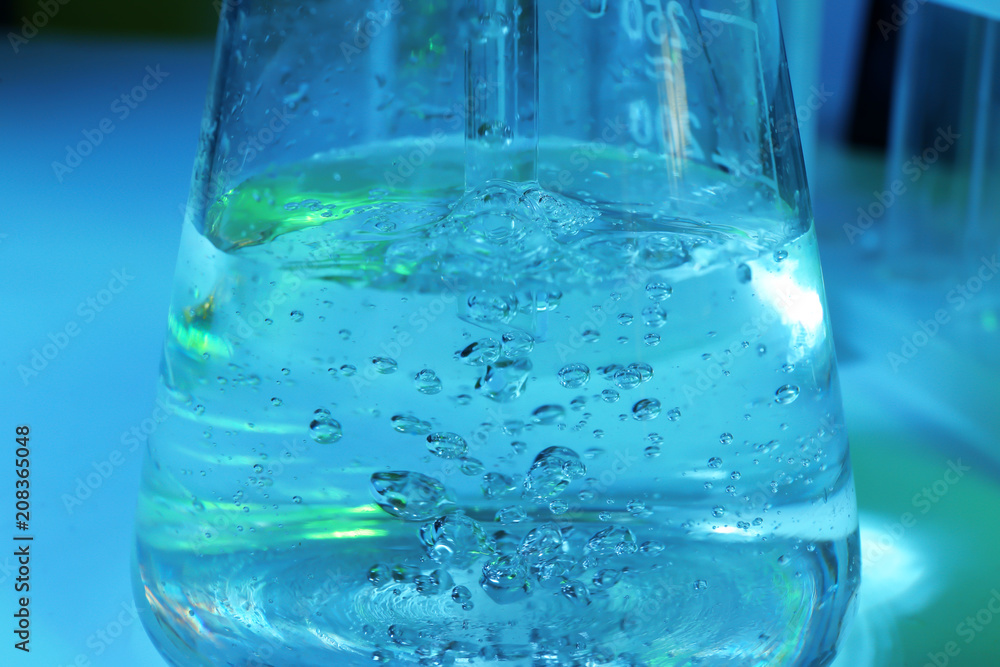 Test flask with water on color background, closeup Test flask with water on color background, closeup