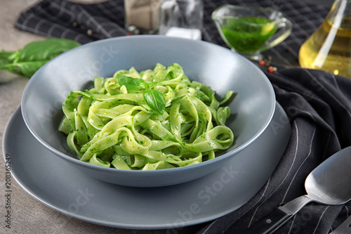 Plate of delicious pasta with pesto sauce on table