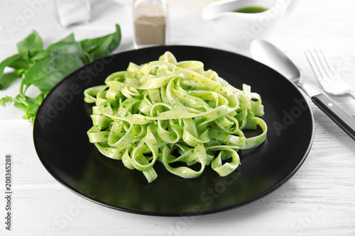 Plate of delicious pasta with pesto sauce on table