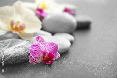 Spa stones and beautiful orchid flowers on grey background