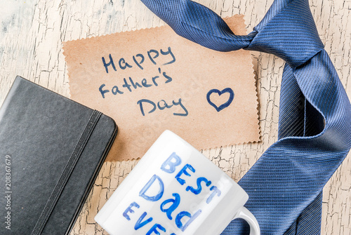 Father's Day gift concept, greeting card background, gift box, tie decoration, mug with inscription Best Dad Ever, notebook, top view