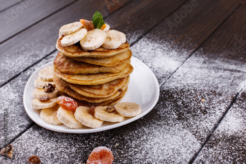 Tasty breakfast. Delicious puncakes with bananas, nuts and mint served on white plate photo