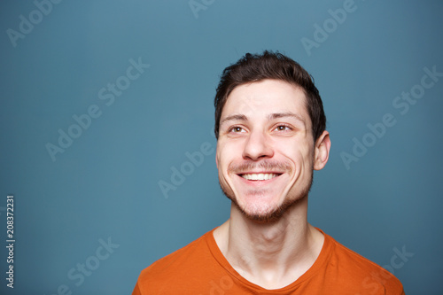 Close up attractive young man against blue background looking up