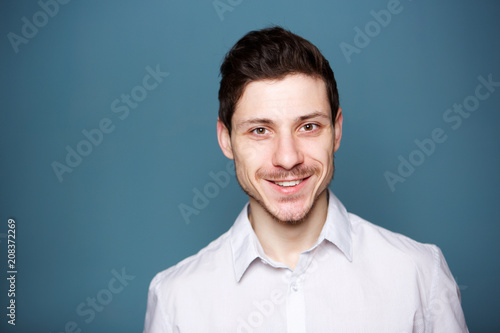 happy young man smiling against blue background