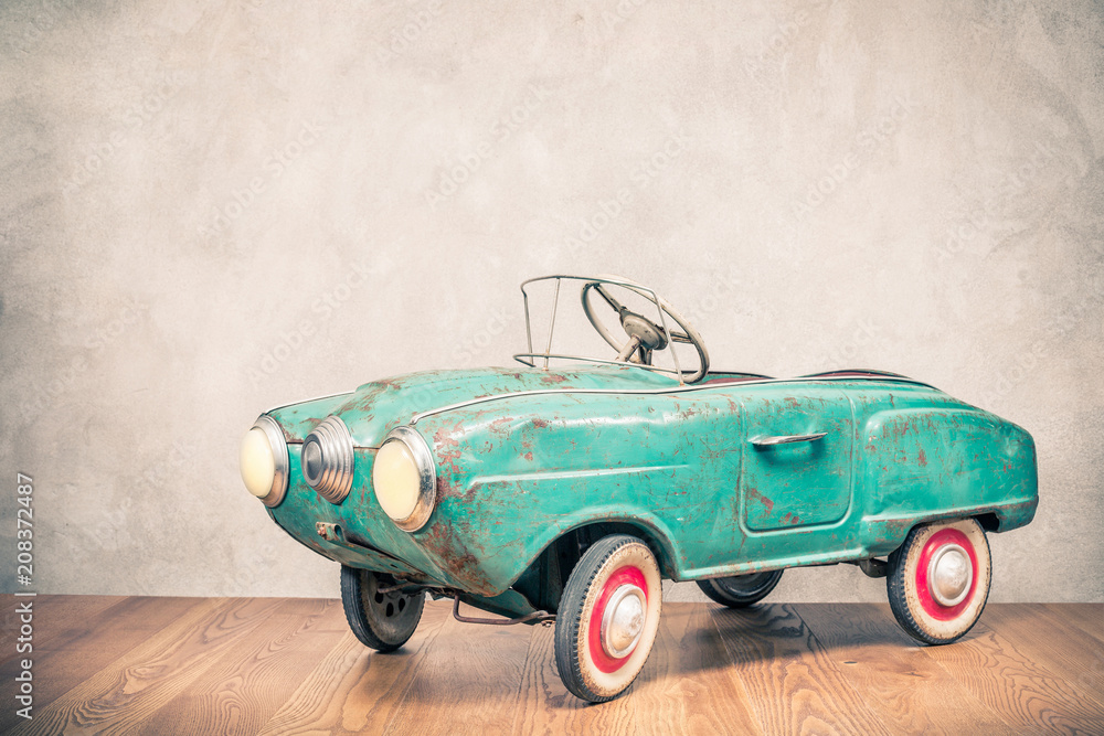 Fototapeta Retro przestarzały zardzewiały metal turkus pedał samochodu zabawka z około późnych lat 60-tych lub wczesnych lat 70-tych z przodu betonu teksturowane tło ściany. Filtruj zdjęcie w stylu vintage