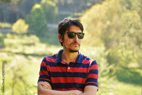 Young man's outdoors portrait looking at the camera with natural green background. Neutral, happy, sad, disgust, fear, surprise Facial Emotions.