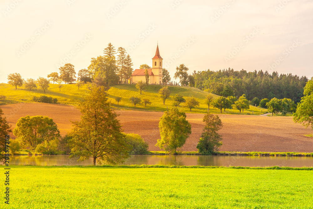 Small church in the middle of lush green spring landscape on sunny day. St. Peter and Pauls church at Bysicky near Lazne Belohrad, Czech Republic.