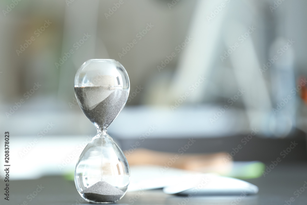 Hourglass on table against blurred background. Time management concept Hourglass on table against blurred background. Time management concept
