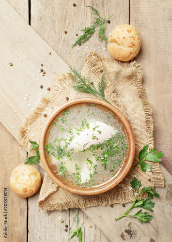Homemade chicken broth with white meat and herbs, rustic style, vintage wooden background, top view