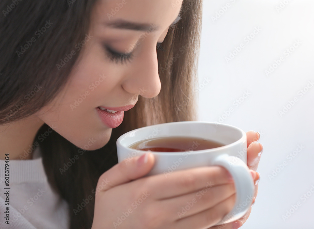Beautiful young woman with cup of hot tea at home, closeup Beautiful young woman with cup of hot tea at home, closeup