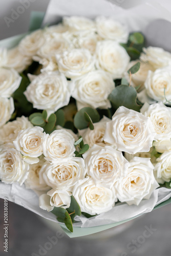 white spray roses. Bouquet of beautiful flowers on wooden table. Floristry concept. the work of the florist at a flower shop. Vertical photo