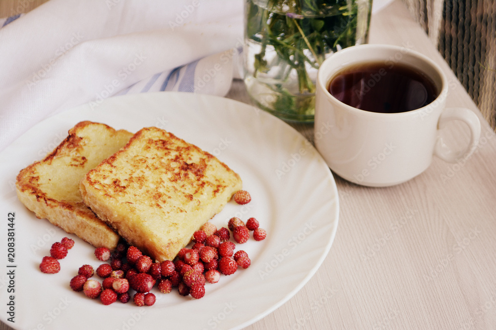 Breakfast. Croutons or toasts with berries (wild strawberry) and tea on a wooden background. Toned Breakfast. Croutons or toasts with berries (wild strawberry) and tea on a wooden background. Toned