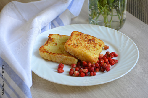 Breakfast. Croutons or toast bread with berries (wild strawberry) and tea on a wooden background.