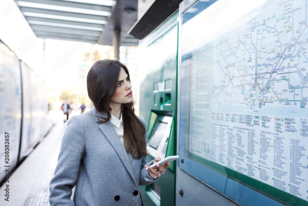 Spain, Barcelona, young woman with smartphone looking at map at station Spain, Barcelona, young woman with smartphone looking at map at station