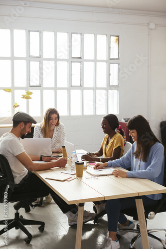 Smiling colleagues working together at desk in office