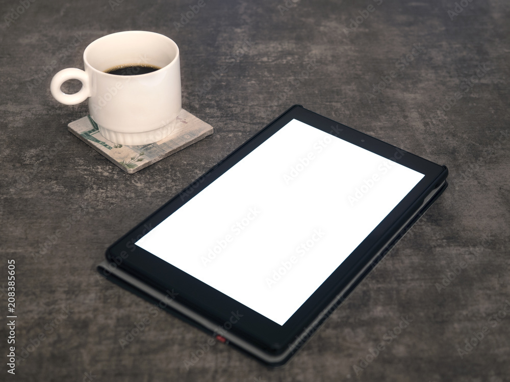 Blank screen tablet mock up on a wooden surface and a cup of coffee on the side Blank screen tablet mock up on a wooden surface and a cup of coffee on the side