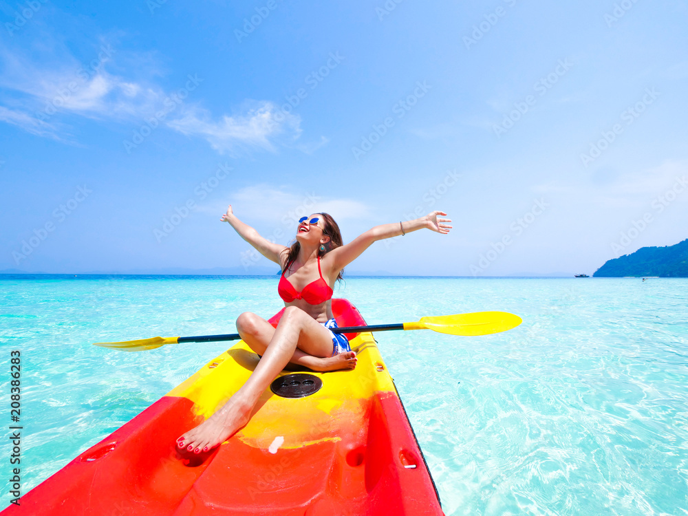 Naklejka premium Asian woman on the kayak boat in Andaman blue sea and blue sky background location in Phuket island Thailand