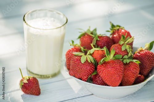 Ripe strawberries and a glass of milk on a light background. Natural simple food. 