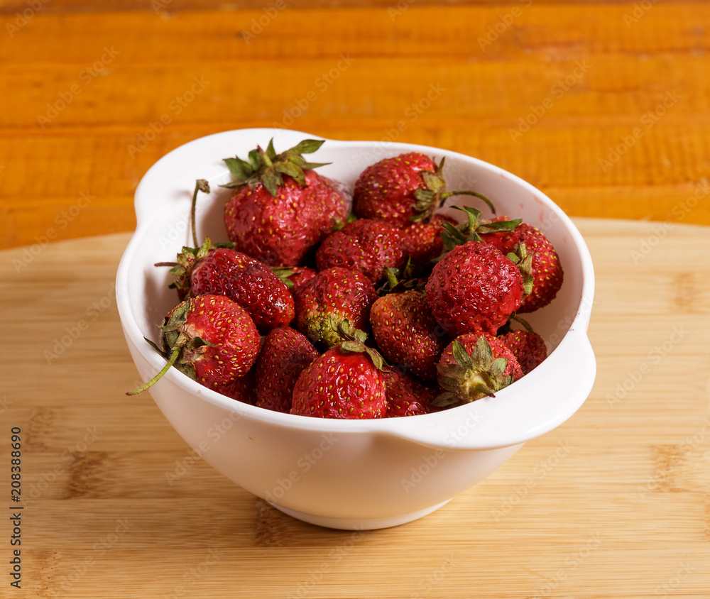 Red strawberries in a deep white plate.