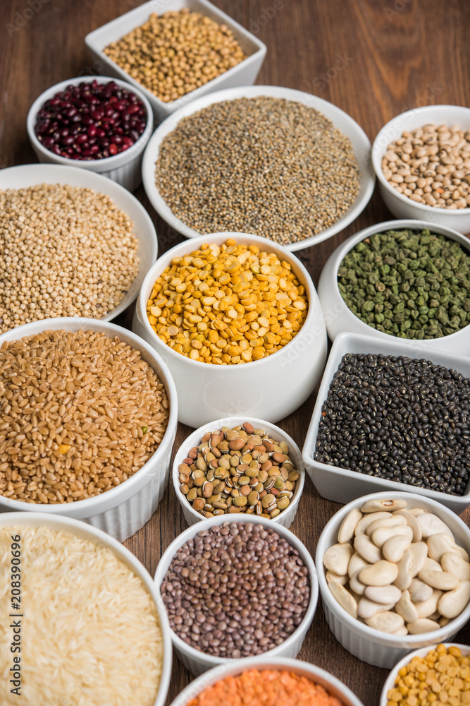 Uncooked pulses,grains and seeds in White bowls over wooden background. selective focus Uncooked pulses,grains and seeds in White bowls over wooden background. selective focus