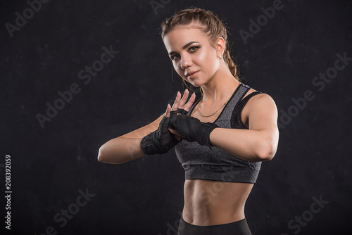  Beautiful sportswoman in boxing bandages on a black background