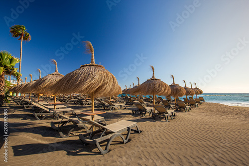 Sun umbrellas Torviscas Beach (Playa de Torviscas), near El Duque Castle, Tenerife, Spain. photo