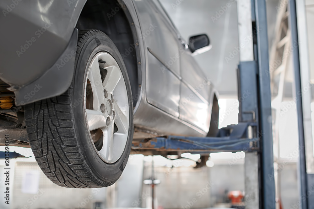 Car on lift at service center, closeup Car on lift at service center, closeup