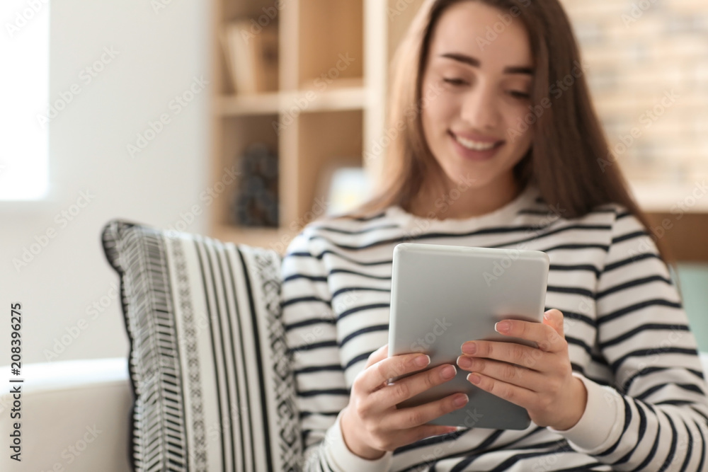 Young woman using tablet while resting on sofa at home Young woman using tablet while resting on sofa at home