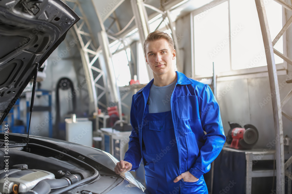 Portrait of male mechanic near car in service center Portrait of male mechanic near car in service center