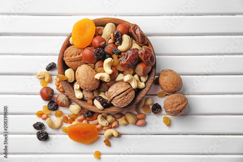 Fototapeta Naklejka Na Ścianę i Meble -  Plate with different nuts and dried fruits on wooden table, top view