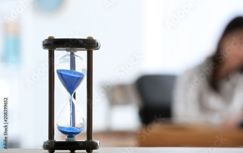 Hourglass and blurred woman on background. Time management concept