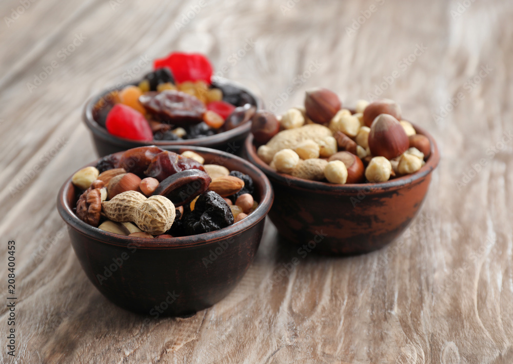 Bowls with mix of dried fruits, berries and nuts on wooden background Bowls with mix of dried fruits, berries and nuts on wooden background